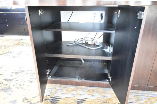 Wooden counter with open doors, featuring interior shelves and a visible power strip. Good condition.