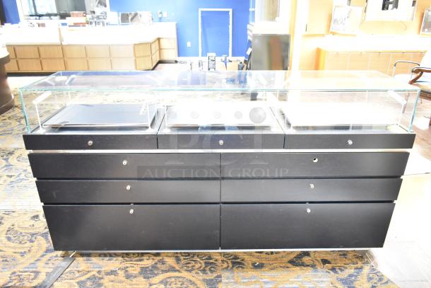 Black jewelry case with six rear drawers and a glass display top. Used condition. Buyer responsible for removal.