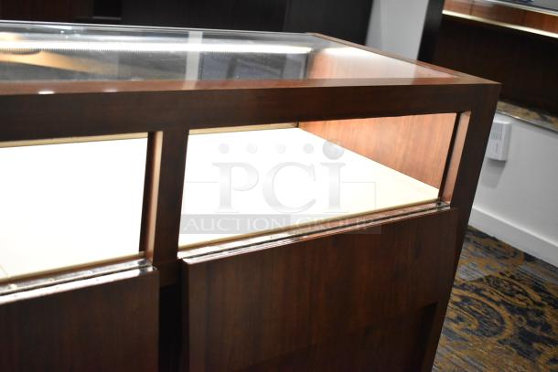 Wooden lighted jewelry case with glass top and two rear doors, in good condition. Buyer must bring tools for removal.