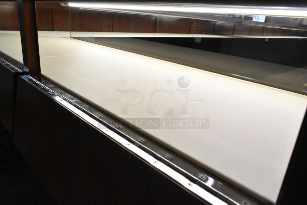 Wooden lighted jewelry case with two rear doors, glass top, and metallic trim. Requires manual removal. Good condition.