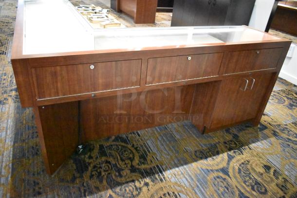 Wooden lighted jewelry case with two rear doors, glass top, and lockable drawers. Good condition. Tools needed for removal.