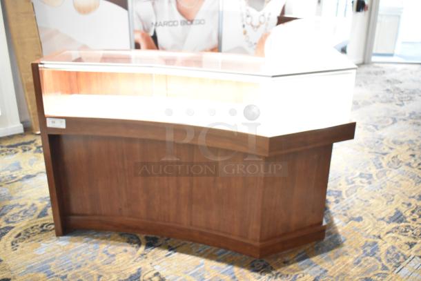 Wooden lighted jewelry case with four rear doors, curved design, and glass display top. Tool removal required.