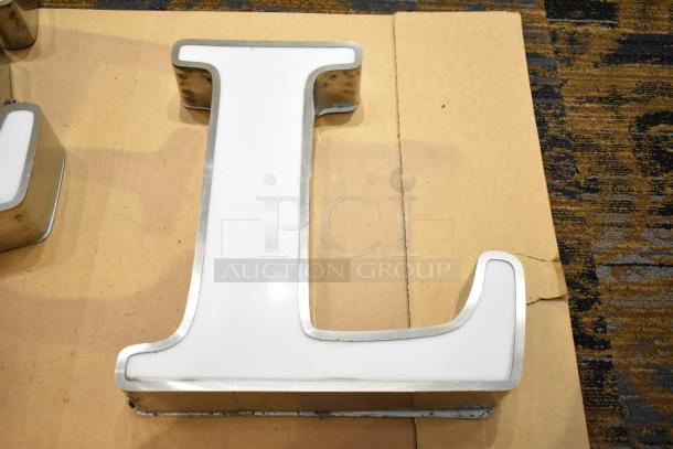 White letter "L" with silver finish frame, showcasing a glossy surface and robust construction, suitable for signage.