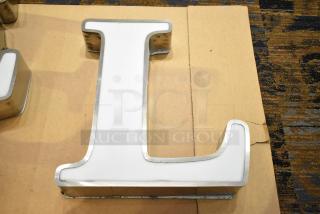 White letter "L" with silver finish frame, showcasing a glossy surface and robust construction, suitable for signage.