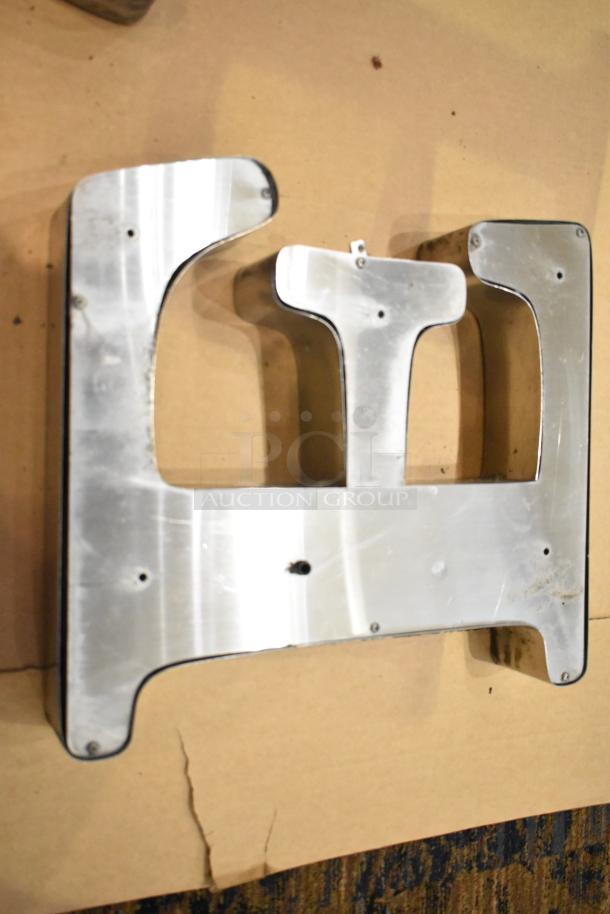 White letter "E" with silver finish frame, vintage marquee style, featuring visible mounting holes and minor surface wear.