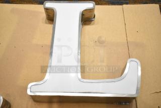 White letter "L" with silver finish frame, in good condition, on cardboard. Ideal for decorative purposes.