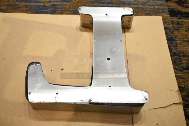 White "L" letter with silver finish frame, featuring visible screws and slight wear, placed on a cardboard surface.