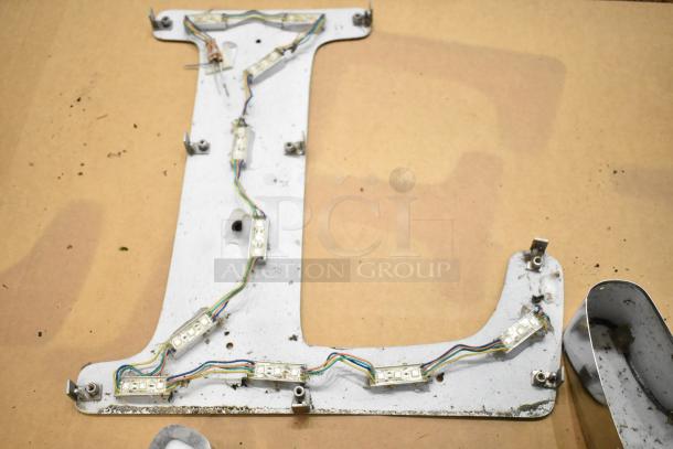 White L letter with silver finish frame, visible wiring, and mounting brackets, shows wear. Suitable for signage or decor.