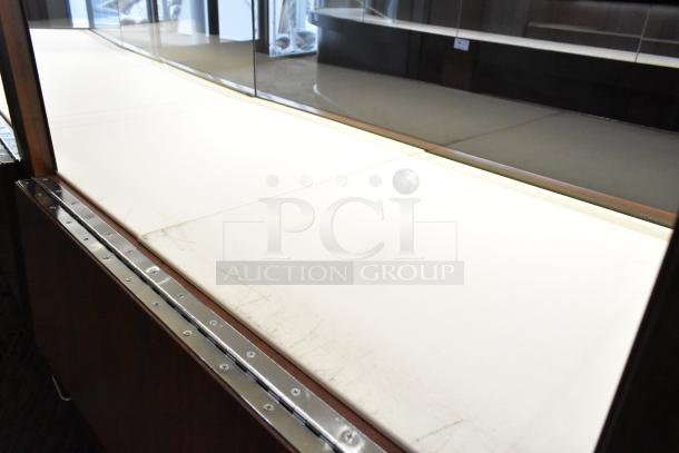 Lighted wooden jewelry display case with six rear doors and three drawers. Slight wear on interior surface. Buyer must remove.