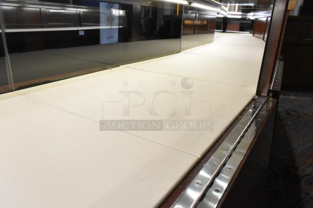 Lighted wooden jewelry display case with 6 rear doors and 3 drawers, glass top, and metal trim in fair condition.