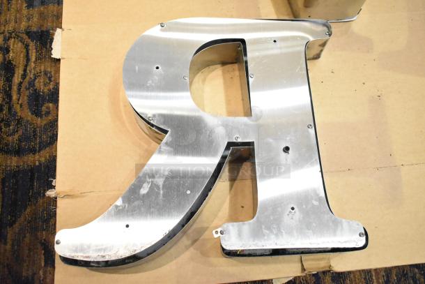White letter "R" with silver finish frame, exhibiting minor wear, suitable for signage or decor use.