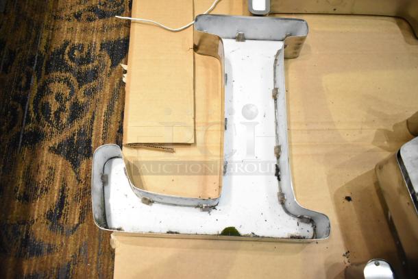 White "L" letter with silver finish frame, showing some wear. Ideal for signage or decor.