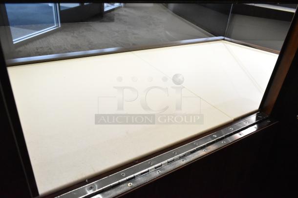 Lighted wooden jewelry display case with glass top, two rear doors, metal hinges. Good condition, tools required for removal.