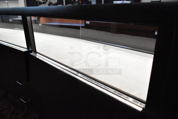 Lighted curved wooden jewelry display case with glass front, rear doors, and drawers; good condition. Buyer removal required.