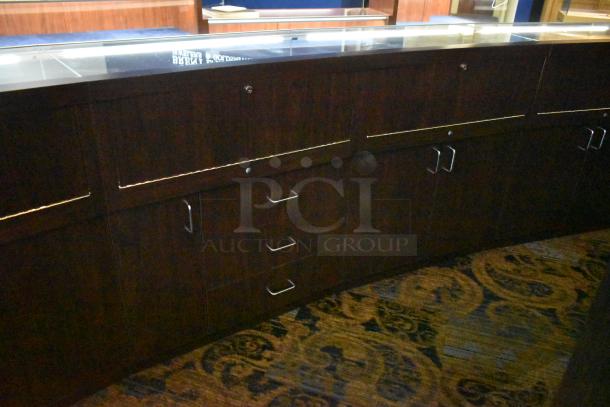 Lighted curved wooden jewelry display case with rear doors and drawers, in good condition, suitable for merchandising.