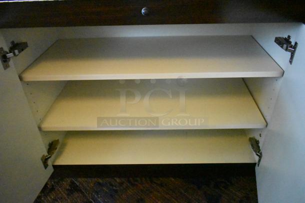 Lighted curved wooden jewelry display case with rear doors and drawers, interior shelves visible. Buyer must remove.