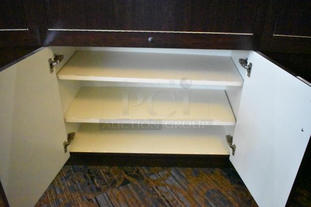Lighted curved wooden jewelry display case with 4 rear doors, interior shelves, brown finish. Buyer must remove it.