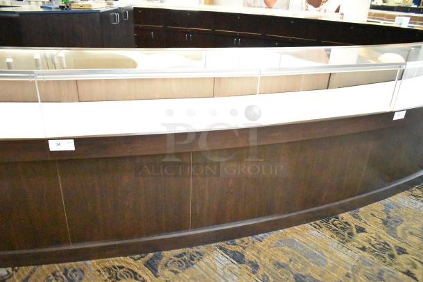 Lighted curved wooden jewelry display case with 4 rear doors, glass top, good condition. Buyer to remove with tools and manpower.