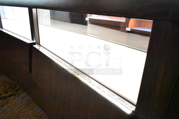 Lighted curved wooden jewelry display case with glass panels, four rear doors, and modern design. Buyer must remove.