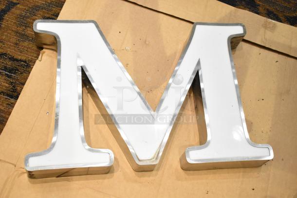 White letter "M" with silver finish frame, used condition. Ideal for decoration or signage.