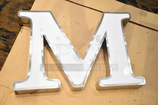 White letter "M" with silver finish frame, used condition. Ideal for decoration or signage.