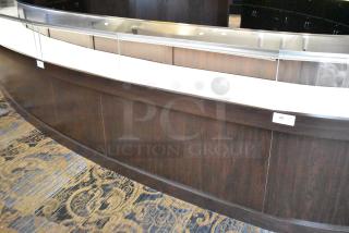 Curved wooden jewelry case with glass top, three rear doors, and three drawers. Lighted interior. Buyer removes.