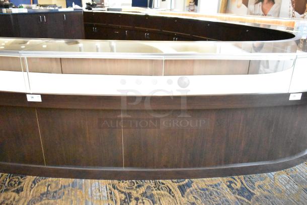 Wooden lighted jewelry case with three rear doors and three drawers. Dark wood finish, glass top, good condition. Removal required.