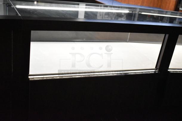 Wooden lighted jewelry case with glass top, featuring 3 rear doors and 3 drawers, in need of removal.