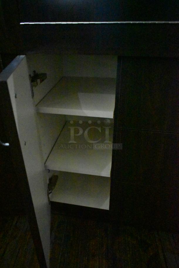 Wooden lighted jewelry case, features three rear doors and three drawers. Buyer must remove; bring tools and manpower.