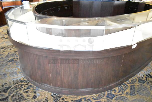 Wooden curved lighted jewelry case with glass front, four rear doors, dark wood finish, in good condition.