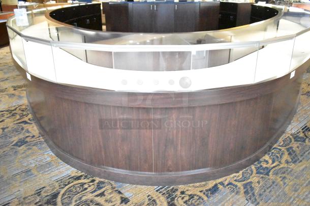 Curved wooden lighted jewelry case with glass top and four rear doors, in good condition. Buyer must bring tools for removal.