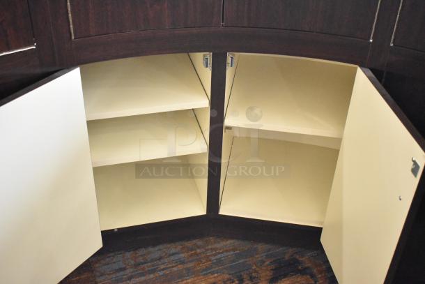 Wooden curved lighted jewelry case with four rear doors, open to show interior shelving. Dark wood finish, good condition.