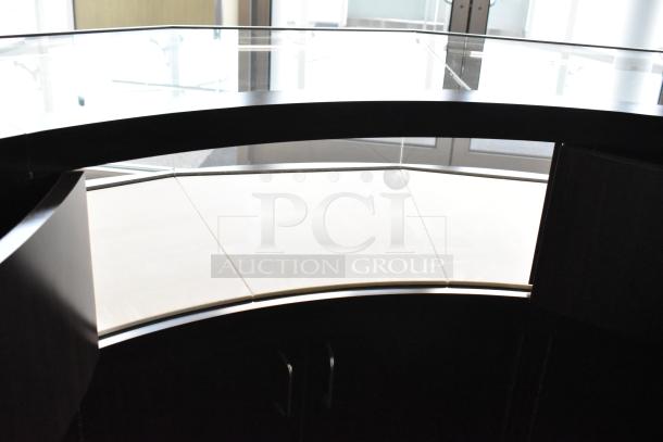 Wooden curved jewelry display case with lighting, featuring glass top and four rear doors. Requires manual removal.