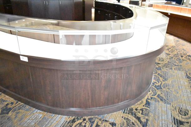 Wooden curved lighted jewelry case with four rear doors. Excellent condition. Buyer must provide tools and manpower for removal.