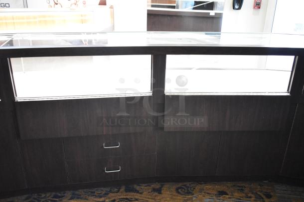 Wooden lighted jewelry display case with glass top, three rear doors, and three drawers, in good condition.