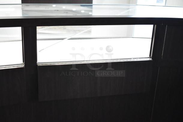 Wooden lighted jewelry case with glass top, featuring three rear doors and three drawers. Condition appears good.