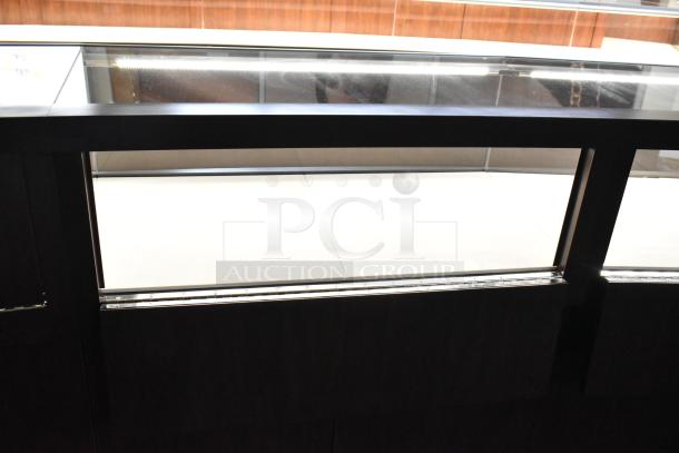 Wooden lighted jewelry case with glass front, four rear doors, and spacious interior. Buyer must remove. Tools needed.