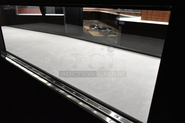 Wooden lighted jewelry case with three rear doors and three drawers. Buyer must provide tools for removal.