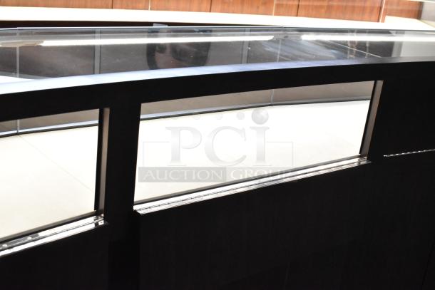 Wooden lighted jewelry case with glass top, featuring 3 rear doors and 3 drawers. Buyer removal required.