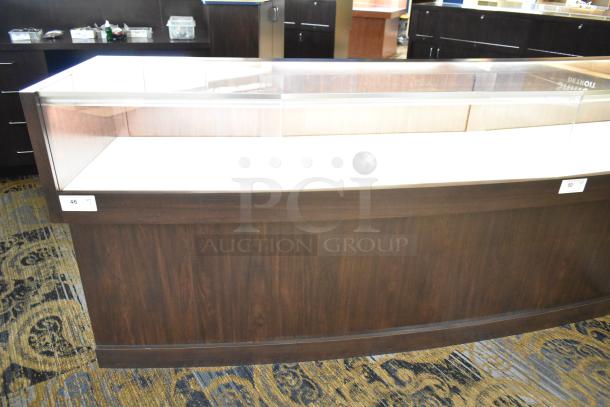 Wooden lighted jewelry case with four rear doors, good condition. Buyer must bring tools and manpower for removal.