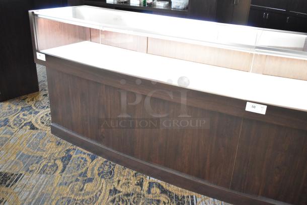 Wooden lighted jewelry case with four rear doors, dark finish, glass top, tags indicate buyer removal required.