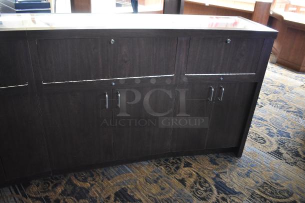 Wooden lighted jewelry case with four rear doors, dark finish, good condition. Buyer must remove with tools and manpower.