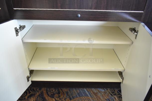 Wooden lighted jewelry case with 4 rear doors, open to show beige interior shelves. Labels read "RINGS," "EARRINGS," "NECKLACES," "BRACELETS."