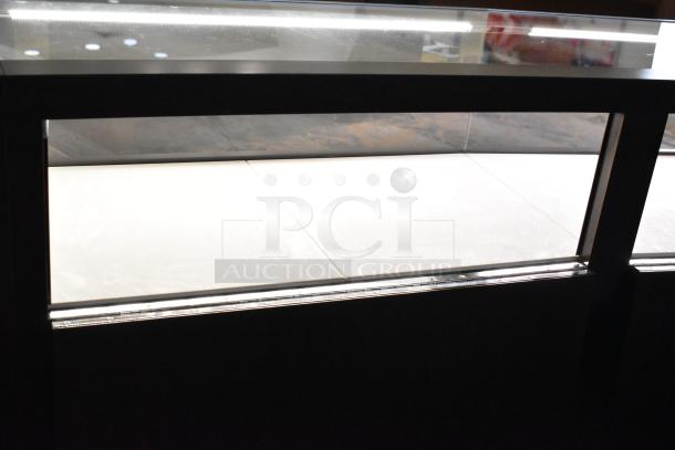 Wooden lighted jewelry case with four rear doors, glass display top, and white interior. Requires removal tools and manpower.