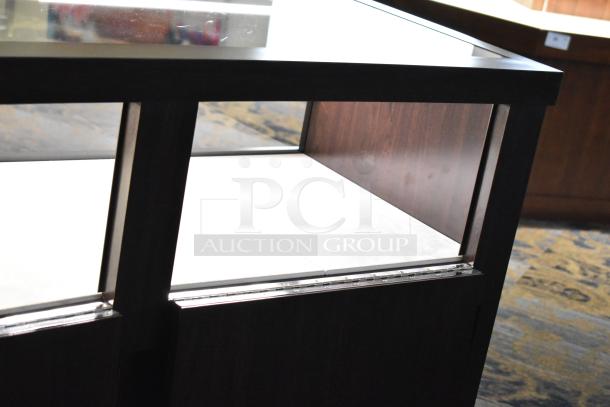 Wooden lighted jewelry case with glass top, featuring four rear doors. Good condition. Removal requires tools and manpower.