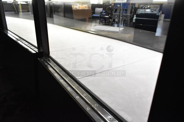 Wooden lighted jewelry display case with four rear doors. Good condition. Buyer responsible for removal; tools required.