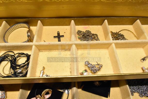 Jewelry case with assorted contents including a watch, pin, and necklaces. Compartments reveal varied jewelry items.