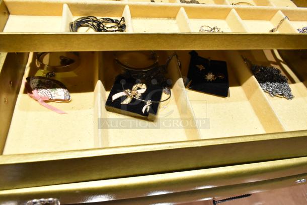 Gold-toned jewelry case with assorted contents including a watch, fan-shaped pin, and necklaces. Excellent condition.