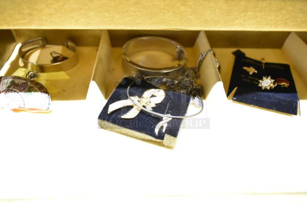 Two jewelry cases containing a watch, pin, and various necklaces. Items shown on velvet display cards.