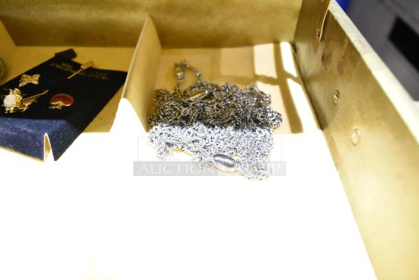 Two jewelry cases with assorted contents, including a watch, pin, and necklaces, displayed in a partitioned box.